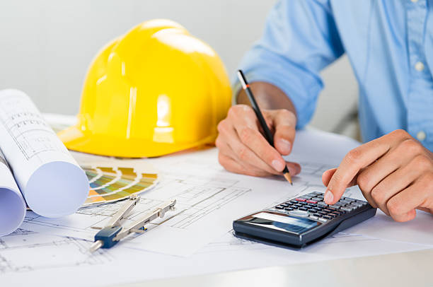 Close Up Of Male Architect Drawing On Blueprint And Using Calculator